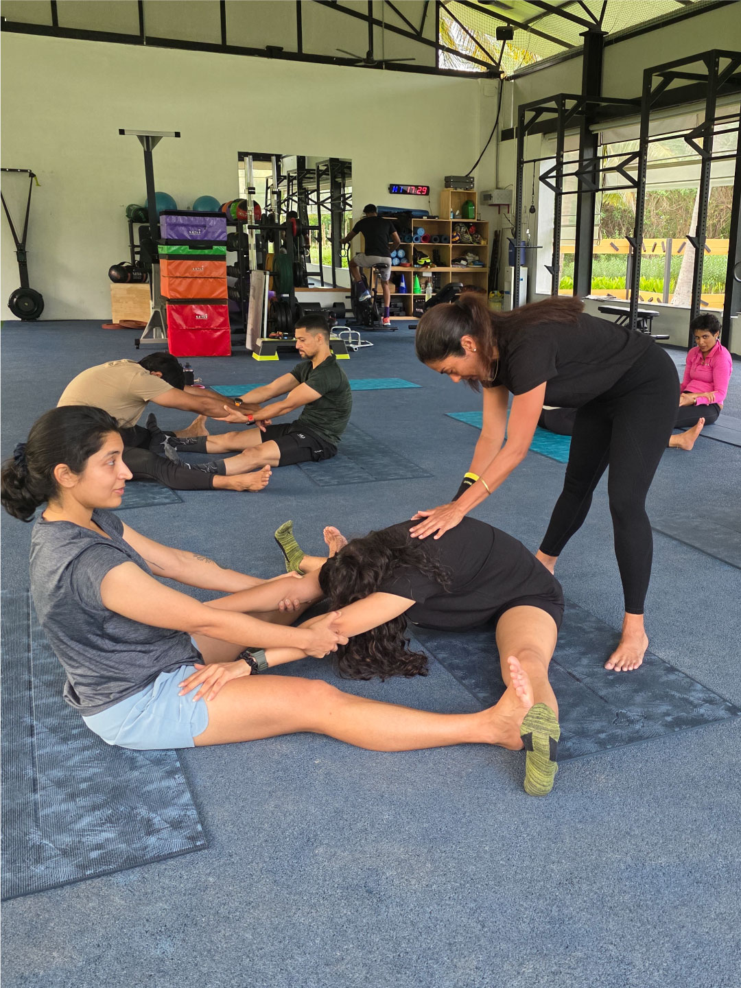 Fitness coach assisting guest in partner stretch at Sol Fitness studio